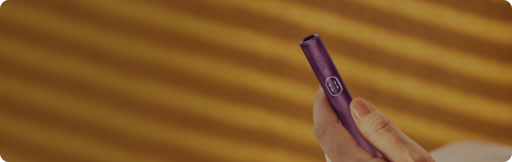 Hand holding a sleek IQOS ILUMA i device against a soft, neutral background.