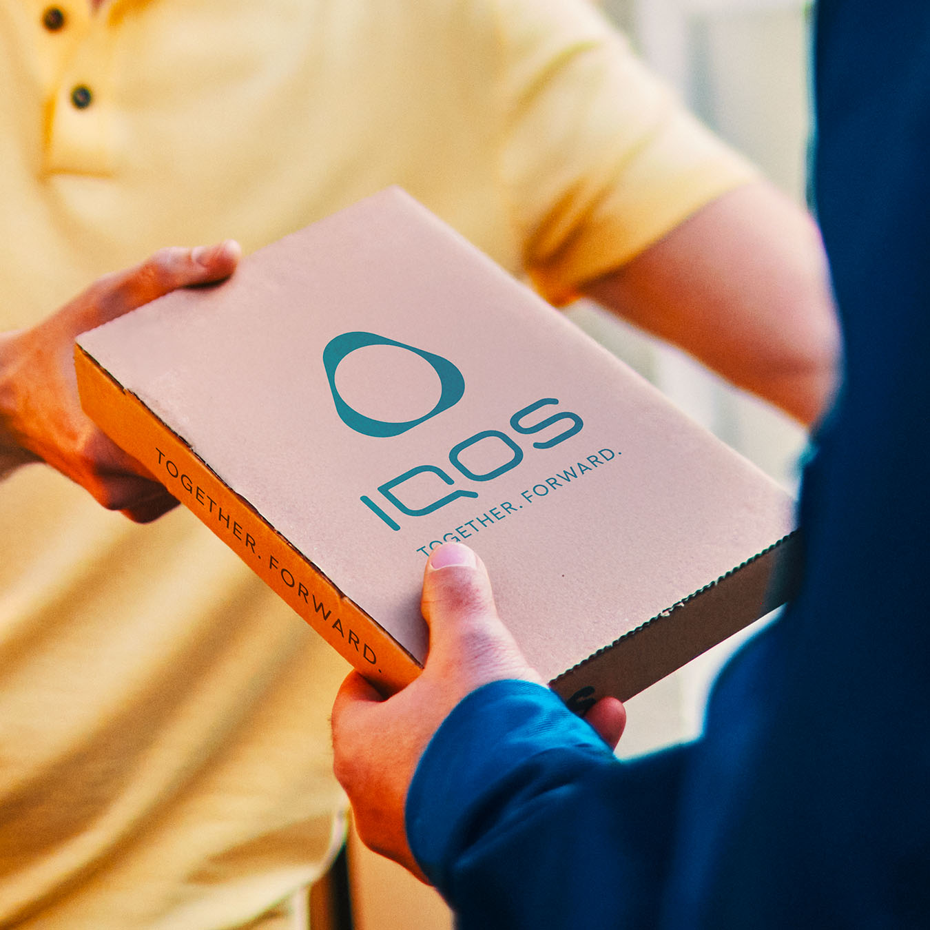 Kurýr předávající balíček se zařízením IQOS