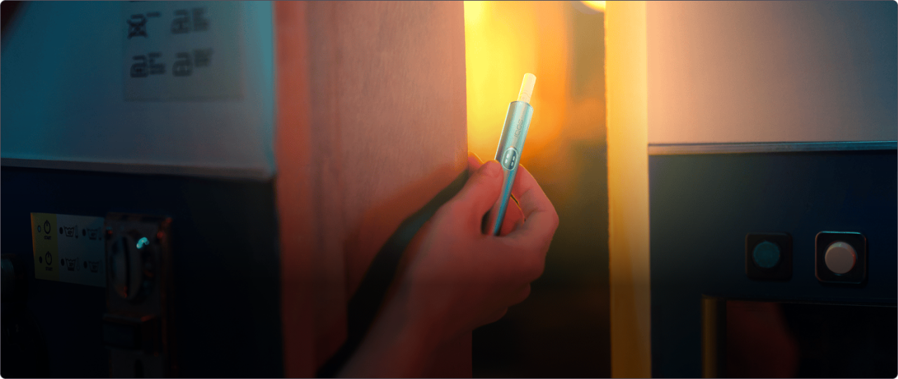 Eine Person hält einen IQOS ILUMA i Holder