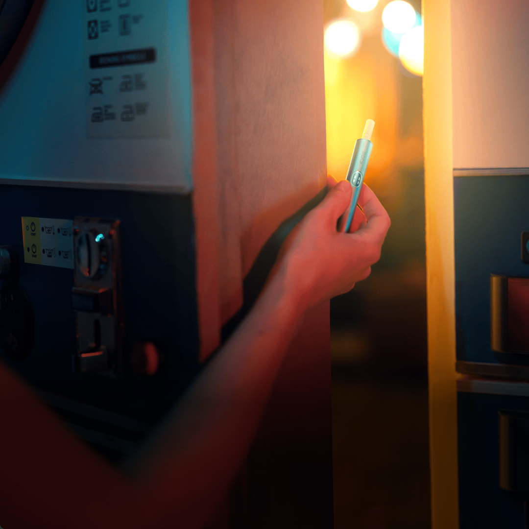 Eine Person hält einen IQOS ILUMA i Holder