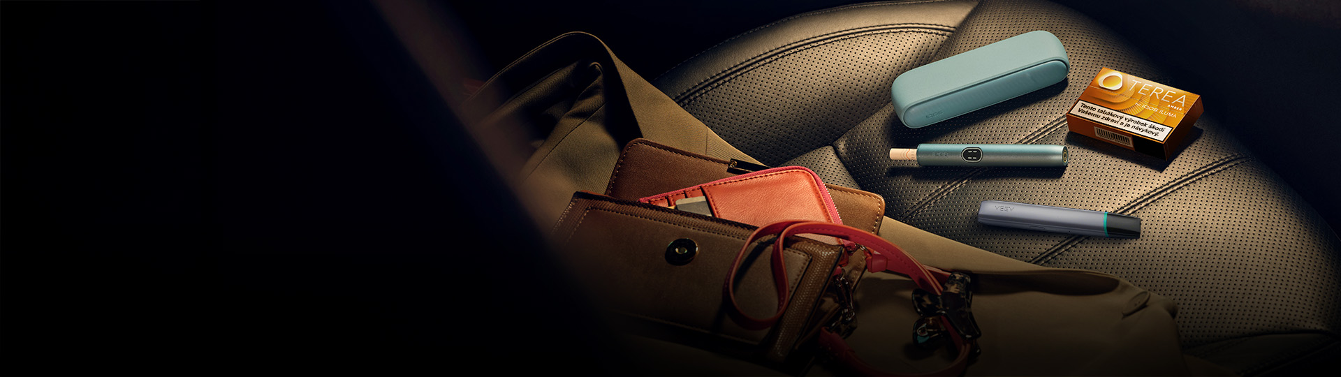 Zařízení IQOS ILUMA i PRIME a VEEV ONE na sedačce auta