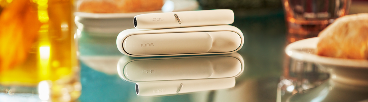 IQOS 3 ležící na skleněném stole při večeři