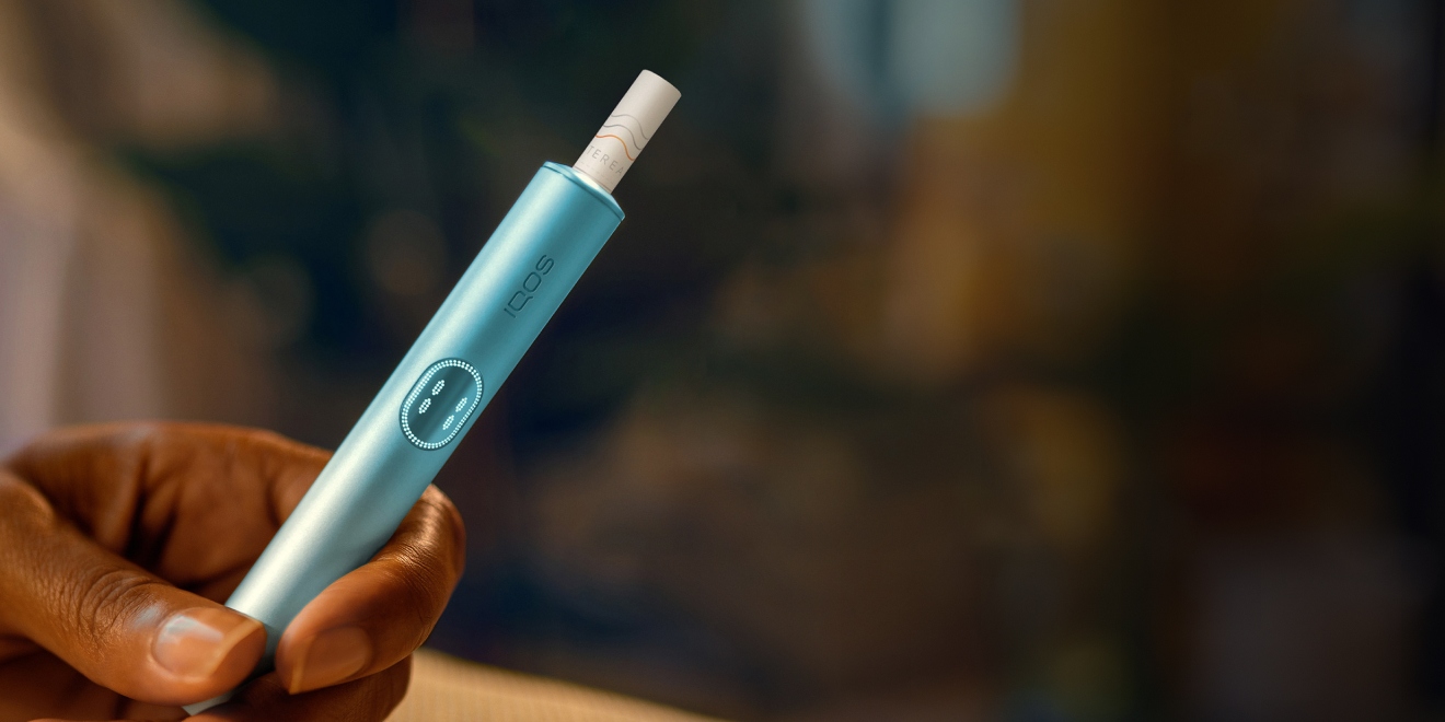 Hand holding an IQOS ILUMA device