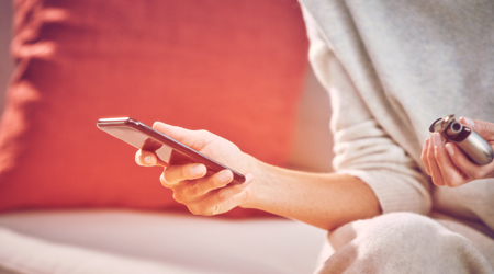 Woman checking her mobile with a IQOS kit in her hand