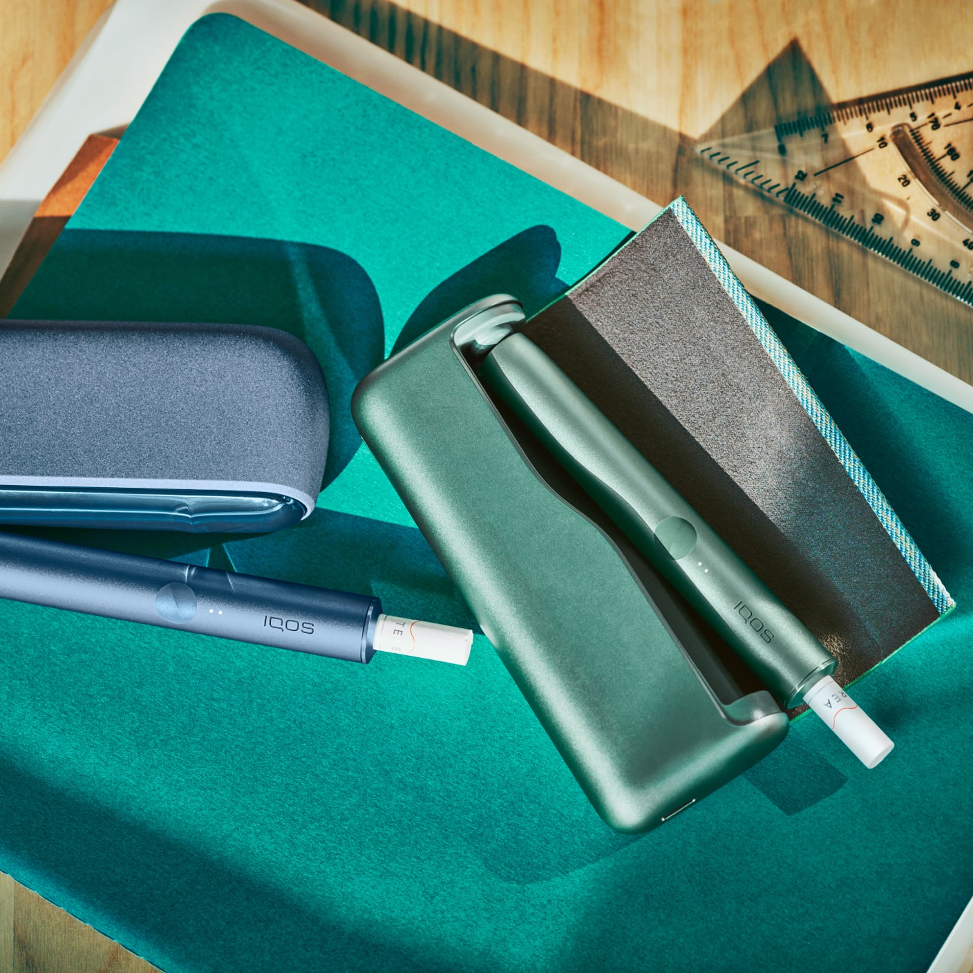 A mid azure blue IQOS ILUMA product sits on an architect's desk.