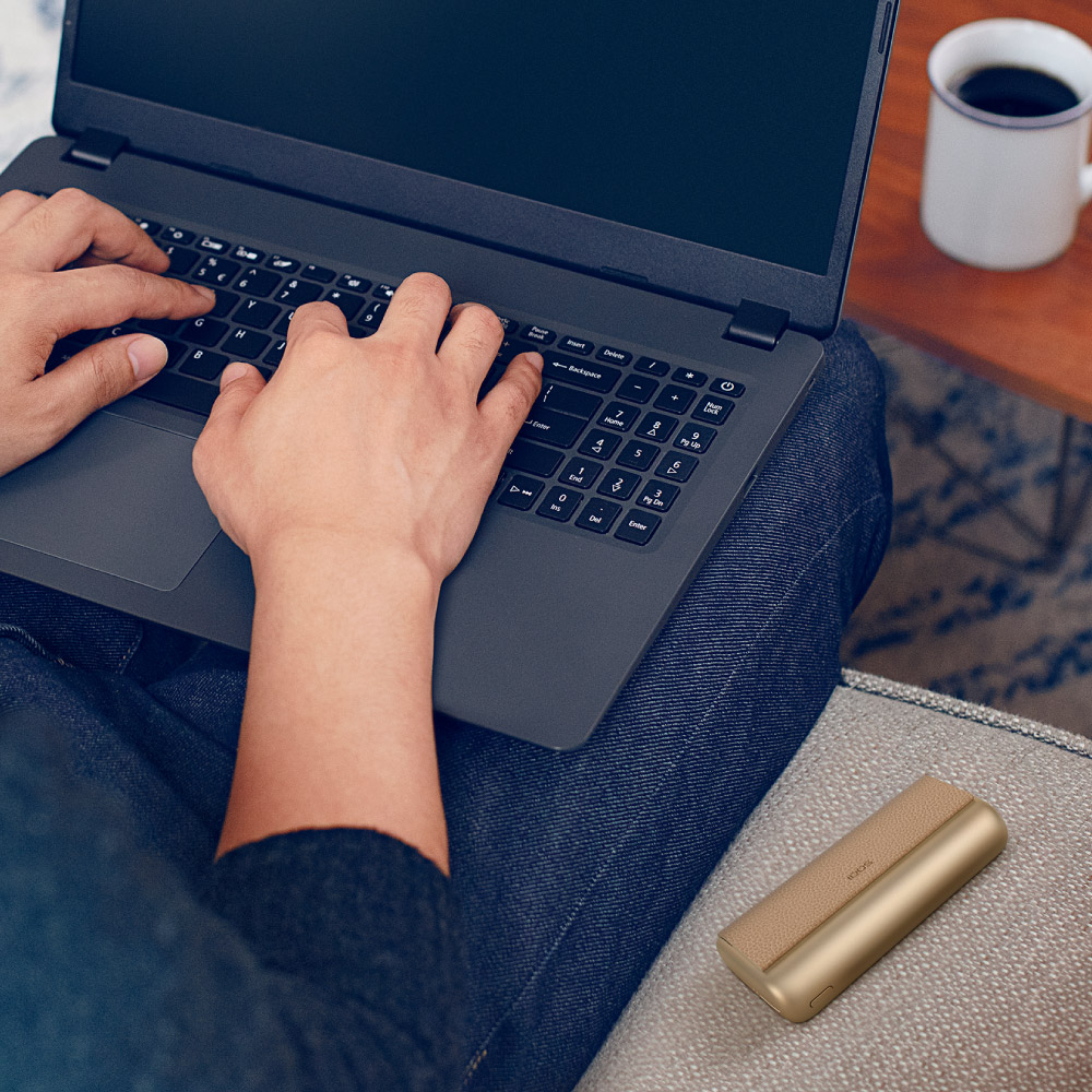 A man conducts online diagnostics for his IQOS ILUMA device using his laptop.